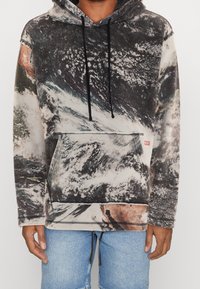 Hoodie in een multiculturele golfpatroon, met een voorzak, koordjes en een merklabel aan de zoom. Zachte stof textuur.