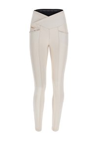 Vaaleanbeige korkeavyötäröiset legginsit, joissa on risteävä vyötärönauha, kaksi sivutaskua, slim fit -leikkaus ja kontrastiväritikkaukset.