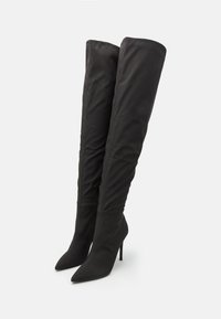 Sorte knæhøje støvler med et slankt, strækbart stof og spidse tæer. Har en høj stilettosandalhæl og en fuld lynlås i siden.