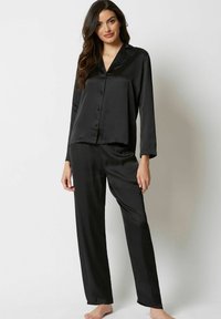 Svart satin pyjamas-set bestående av en långärmad skjorta med knappar och matchande byxor med rak benvidd, båda med en mjuk och slät yta.