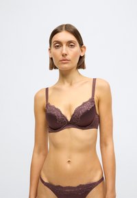 Rudas nėriniuotas liemenėlė su paminkšintais kaušeliais ir reguliuojamomis petnešėlėmis, derantis nėriniuota hipsterinių kelnaičių pora. Minkšta medžiaga, be siūlių dizainas.