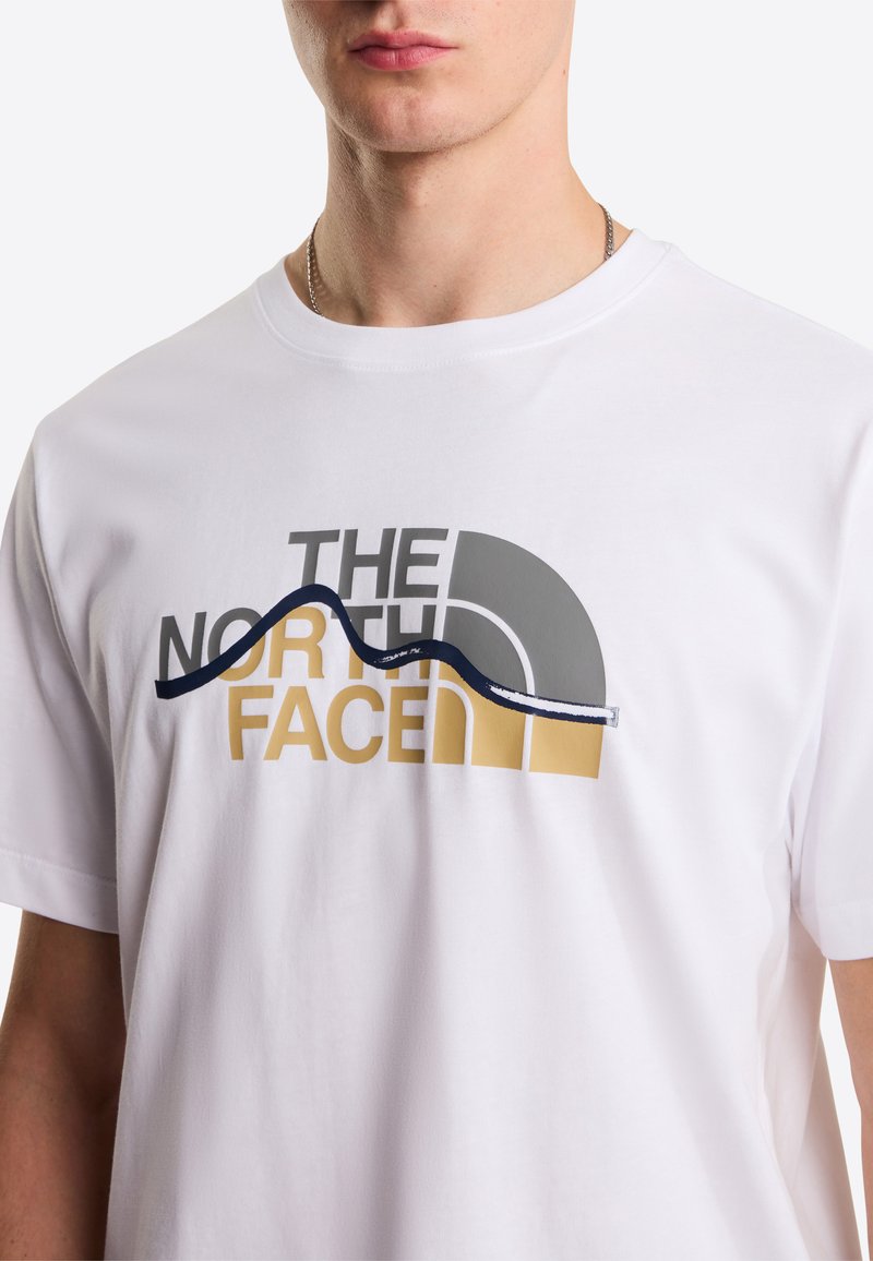 White cotton T-shirt featuring a graphic design with "The North Face" text in black, gray, and gold colors, with wave accents in navy.