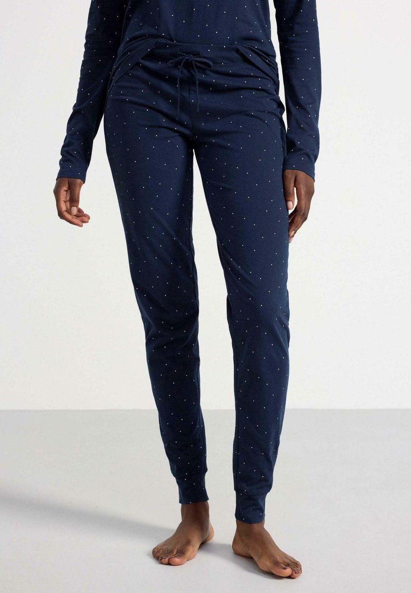 Pyjamas navy avec une taille à cordon, ornés de petits motifs de points blancs, à manches longues et avec un ajustement serré aux poignets et aux chevilles.