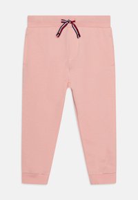 Rosa joggebukser laget av myk bomull. Har snøring med røde, hvite og blå detaljer, oppbrettede ankler og to sidelommer.