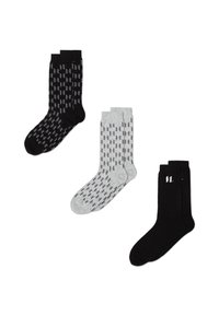 Tre paia di calze: nere con un motivo geometrico, grigie con forme grigie alternate e nere unite con un logo bianco.