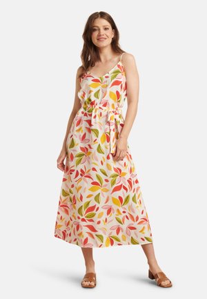 Weißes Maxikleid mit buntem Blättermuster in Rot, Orange und Grün. Mit verstellbaren Spaghettiträgern und einem Bindegürtel. Braune Riemchensandalen.