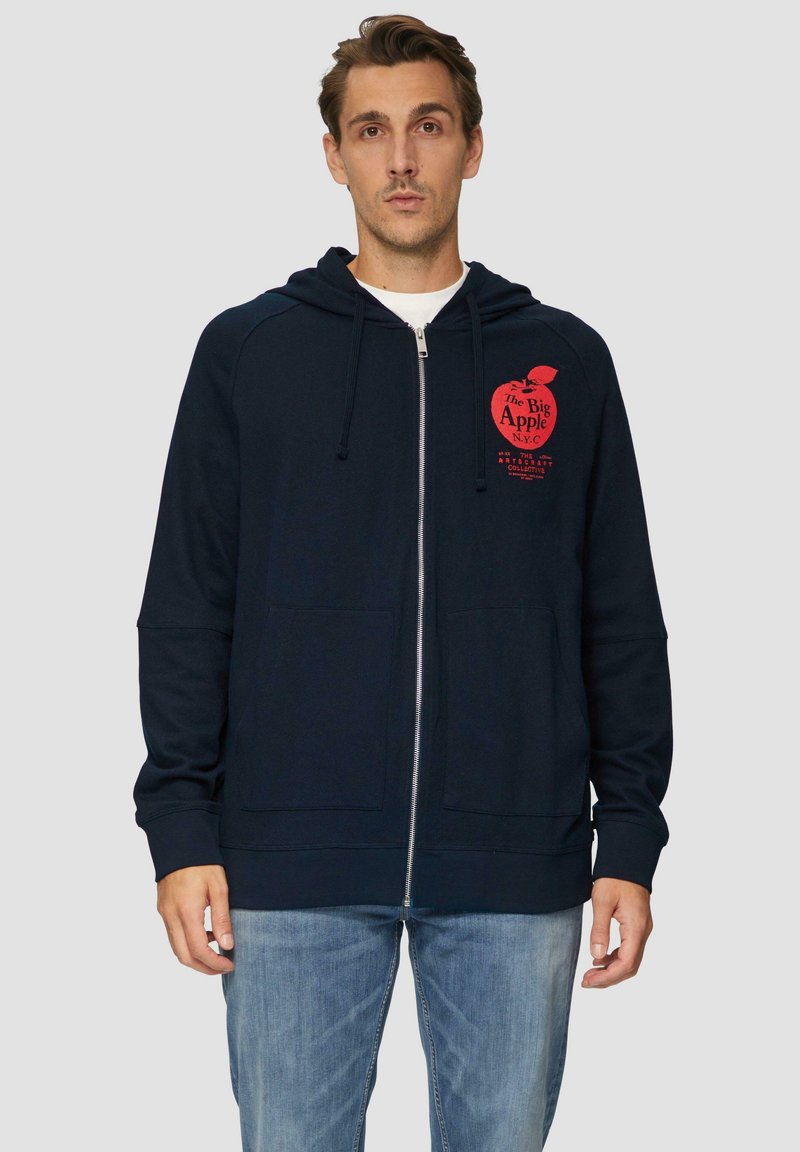 Felpa con zip di colore blu navy con un graphic di una mela rossa e testo. Presenta un cappuccio con coulisse e due tasche frontali. Materiale in cotone morbido.