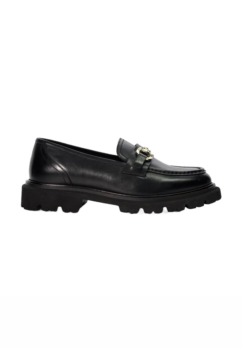 Black leather loafer with a flat, textured sole and a decorative metal buckle accent. Features rounded toe and classic stitching details.