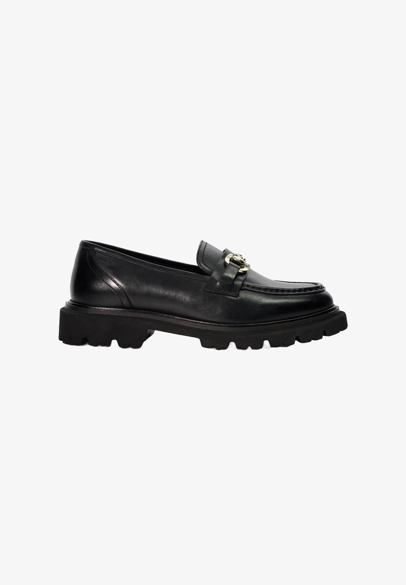 Black leather loafer with a flat, textured sole and a decorative metal buckle accent. Features rounded toe and classic stitching details.