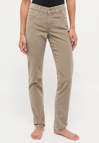 Beige corduroy broek met een aansluitend ontwerp, vijf zakken en een ritssluiting met een metalen knop. Vette textuur met verticale ribbels.