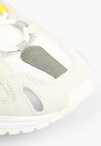 Gros plan sur la zone des orteils d'une sneaker blanche et grise avec un tissu en mesh, des superpositions en daim, et un détail gris cousu près des lacets.