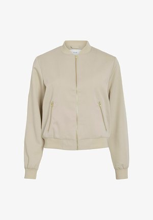 Beżowa kurtka bombka z prążkowanym kołnierzem, mankietami i dołem, złotym suwakiem z przodu oraz dwiema zapinanymi na zamek kieszeniami po bokach.