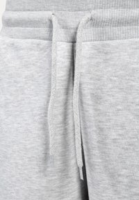 Graue Baumwoll-Jogginghosen verfügen über einen gerippten Bund, Akzente mit Zugband und eine weiche Textur mit einem melierten Muster. Dezente Nähdetails sind sichtbar.