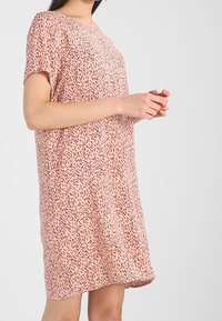 Krátké růžové šaty s jemným černým abstraktním vzorem, volný střih a kulatý výstřih. Lehce, hladký materiál.