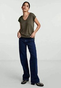 Mörkgrön, kortärmad V-ringad t-shirt i kombination med mörkblå vida jeans och svarta glänsande loafers, med en avslappnad passform och smidig textur.