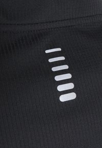 Černá sportovní tkanina má žebrovanou texturu s reflexním logem uspořádaným vertikálně, které se skl�ádá ze sedmi horizontálních pruhů.