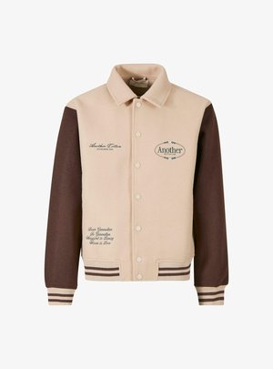 Beige and brown jacket with a button front, collared neck, embroidered text, and striped cuffs. Made of soft fabric, featuring decorative patches.