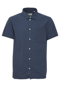 Camisa de manga corta, con botones, en color azul marino, hecha de tela texturizada. Presenta un bolsillo en la parte frontal y botones blancos en contraste.