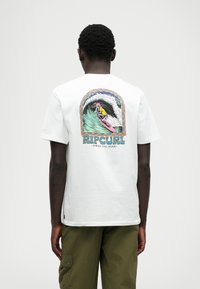 T-shirt en coton blanc avec un graphique de surf coloré au dos, accompagné du texte "RIP CURL" et "SHRED TILL DEAD" en dessous. Manches courtes.