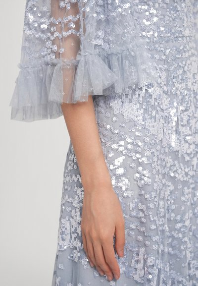 Φόρεμα ανοιχτού γαλάζιου με διακοσμητικά παγιέτες και στρωματοποιημένα μανίκια από τούλι. Διαθέτει εφαρμοστό μπούστο και φαρδιά φούστα που ρέει, προσφέροντας υφή.
