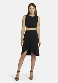 Zwart tweedelig outfit met een nauwsluitende crop top met een ronde halslijn en een knie-lange rok met een gerimpelde zoom en een zijsplit.