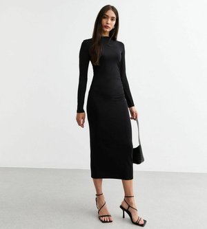 Czarna, długosleeve'owa sukienka dopasowana do ciała, wykonana z elastycznej tkaniny, sięgająca do kolan, z okrągłym dekoltem. Modelka trzyma małą czarną torebkę i nosi sandały na obcasie.