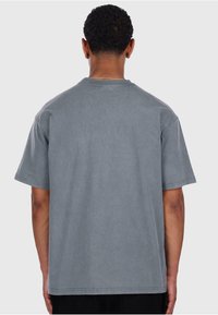 Gray cotton t-shirt with short sleeves, round neckline, and a relaxed fit. The back is plain with no additional patterns or details.