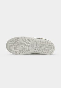 Σόλα λευκού αθλητικού παπουτσιού Nike με κυκλικά και ορθογώνια σχέδια πέλματος και το λογότυπο Nike ανάγλυφο στο κέντρο.