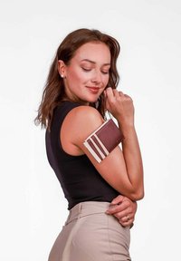 Hn�ědá a béžová peněženka s kontrastními pruhy, vyrobená z kůže, držena na ruce, s řemínkem na zápěstí pro snadné přenášení.