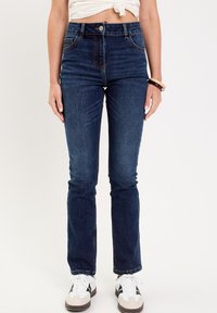 Jeans en denim bleu marine avec une taille ajustée, une coupe droite, des détails de couture subtils et des poches avant et arrière typiques.