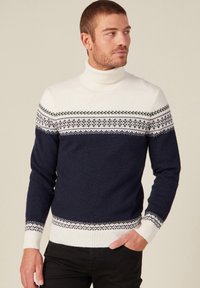 Pull encolure légèrement montant bleu navy et crème avec un design de yoke motif comprenant des accents géométriques ; matière en tricot doux avec des poignets et un ourlet côtelés.
