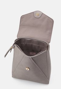 Bolso de mano de ante gris en estilo sobre con cierre dorado, solapa abierta y forro interior de tela visible junto con la etiqueta de la marca.