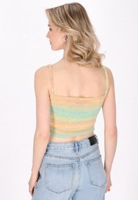 Gebreide cropped top met pastelstrepen in geel, groen en blauw. Heeft dunne bandjes en een gestructureerde afwerking. Gestyled met denim jeans.