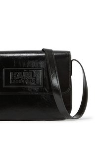 Borsa a tracolla in pelle nera con forma rettangolare, logo impresso e finitura elegante. Include una tracolla piatta e pattina di chiusura.
