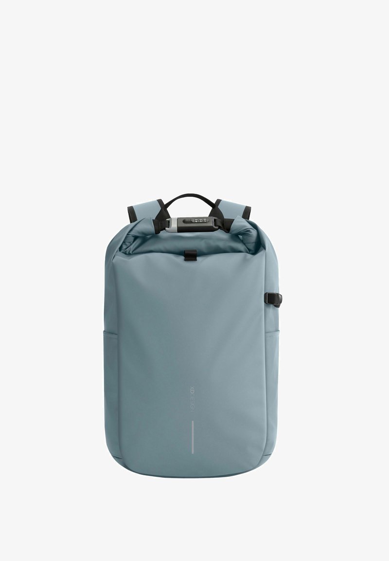 Sac à dos gris avec un design à rabat, fabriqué à partir de matériaux imperméables. Comprend des bretelles réglables, une poche avant et une poignée de transport supérieure.