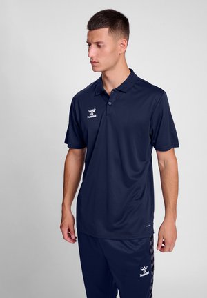 Marineblauwe polo met een kraag, korte mouwen en een logo op de linkerborst. Glad, vochtafvoerend materiaal, gecombineerd met bijpassende broek.