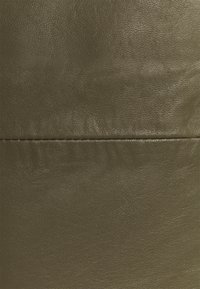 Material de cuero verde oliva con una textura suave, que presenta una costura horizontal y un sutil patrón de grano. Diseño minimalista.