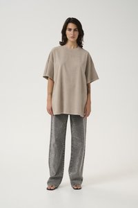Oversized beige cotton t-shirt with short sleeves and crew neck paired with shiny silver wide-leg jeans featuring side embellishments.