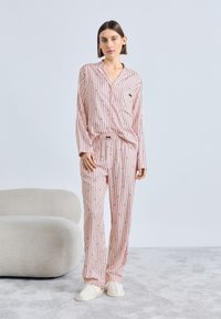 Set de pijamale cu dungi roz și albe, format dintr-o cămașă cu nasturi și pantaloni cu talie elastică, realizat dintr-un material neted și cu o textură moale.