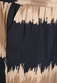 Een gestreepte stof met donkere marineblauwe en beige secties in een penseelstreekontwerp. Zachte textuur met een elastische tailleband en zijzakken.