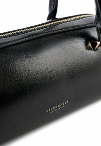 Borsa a mano in pelle nera con superficie testurizzata, ferrature dorate, chiusura a zip e dettaglio logo metallico. Forma cilindrica compatta con manici corti.