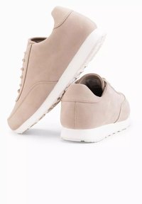 Ljust beige sneakers i mocka med en vit gummisula. Har en enkel snörningsdesign och minimal sömnad på baksidan.