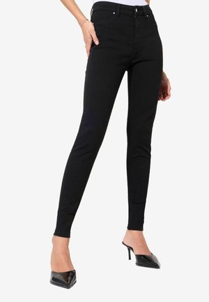 Jean skinny noir fabriqué en tissu extensible avec une taille moyenne, design à cinq poches et accents en métal argenté.