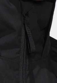 Svart jacka med dragkedja och dragsko vid halsen. Materialet är slätt med en matt yta. Designen är enkel och funktionell.