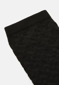 Mustat neulotut sukat, joissa on ribbausvarsia ja teksturoitu kuosi. Materiaali on pehmeä ja siinä on hienovarainen kolmiulotteinen kuvio.