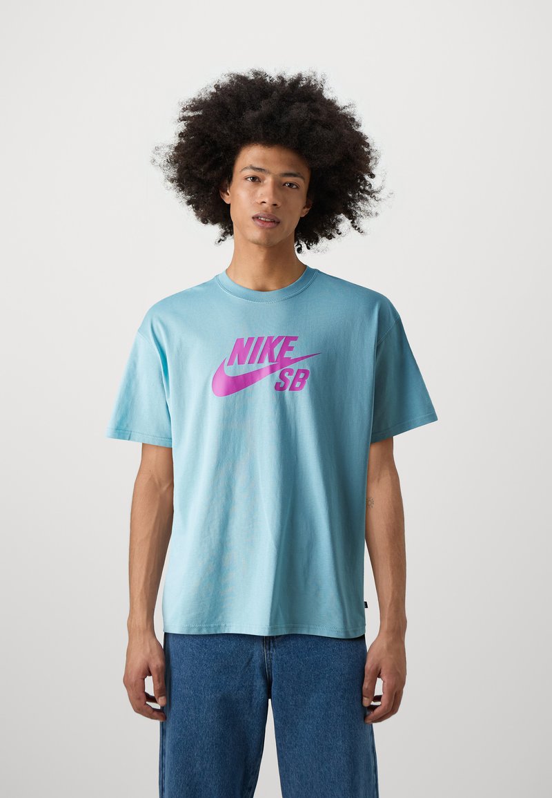 Svetlo modra bombažna majica s kratkimi rokavi, ki ima na sprednji strani velik roza Nike SB logo ter krožni izrez.