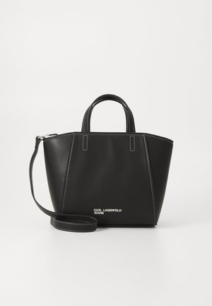 Must lõuendist kott kaarekujulise ülaosaga, kahe käepidemega ja eemaldatava õlarihmaga. Omab valgeid õmblusi ja logo põhjas.