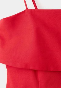 Robe rouge vif sans manches avec fines bretelles et un détail à volants superposés sur la poitrine et la taille.