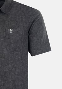 Polo à manches courtes en tissu gris foncé avec un tissage texturé, comportant une poche sur la poitrine gauche et une petite broderie de logo au-dessus.