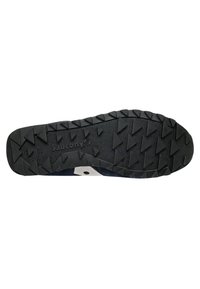 Suola di scarpa nera in gomma con scanalature triangolari profonde, caratterizzata da un logo bianco prominente al centro e una superficie testurizzata per la presa.